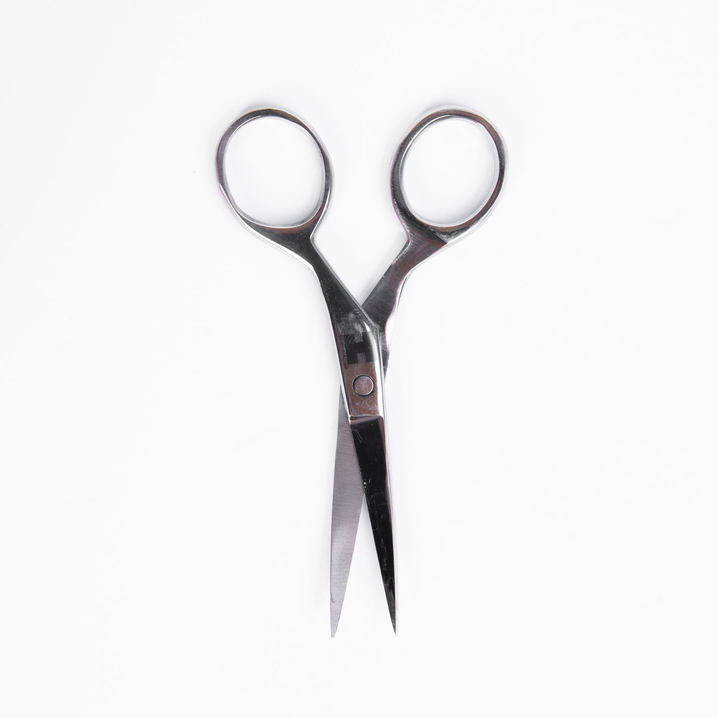 A close-up view of a pair of scissors positioned on a plain white background.