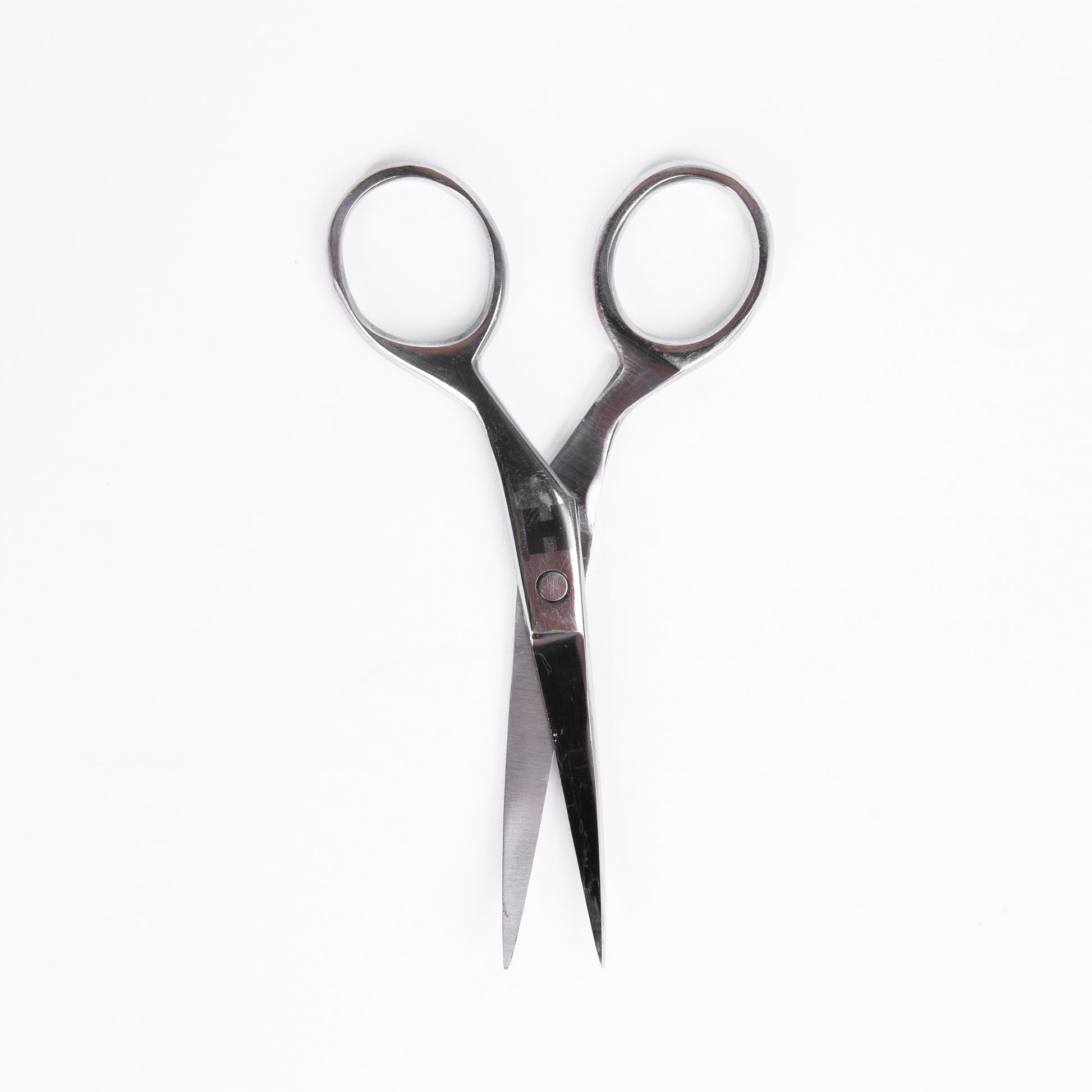 A close-up view of a pair of scissors positioned on a plain white background.