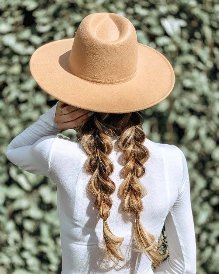 A woman with braids is seen from the back, wearing a stylish hat that complements her hairstyle.