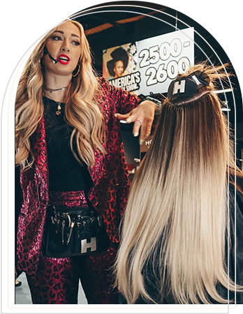 A woman sitting in a salon chair, having her hair styled by a professional hairstylist.
