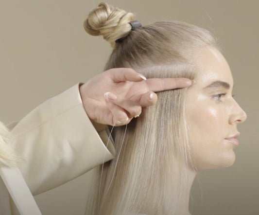 A woman receives a hair styling session, focusing on the application of an anchor bead technique by her stylist.