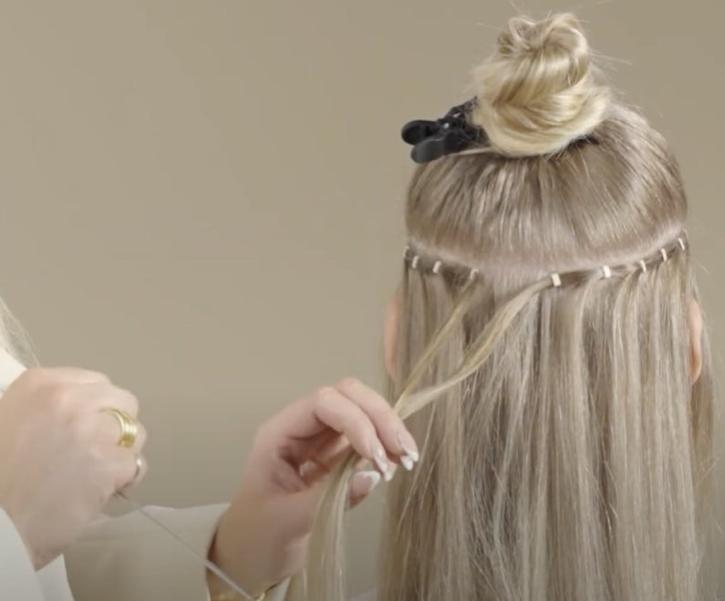 A woman is skillfully applying hair extensions for a stylish transformation.