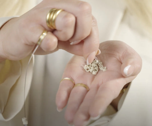 A woman delicately holds a small piece of jewelry, showcasing its intricate design and elegance in her hand.